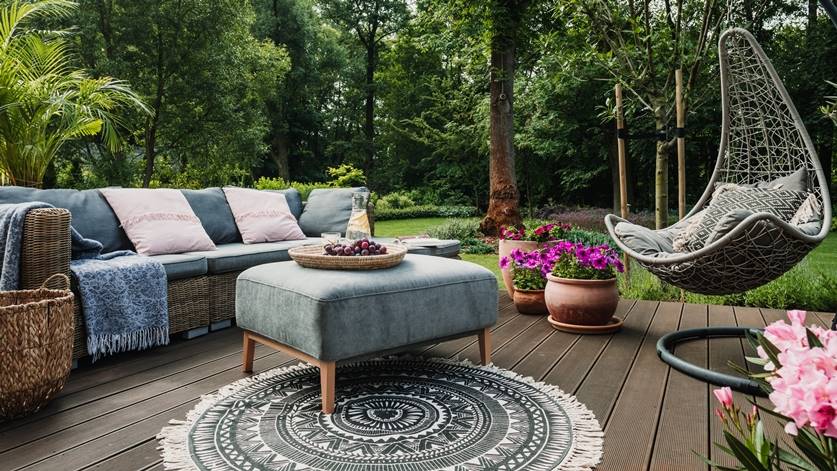 Cosy patio with a hanging chair, sofa, and vibrant plants on a wooden deck