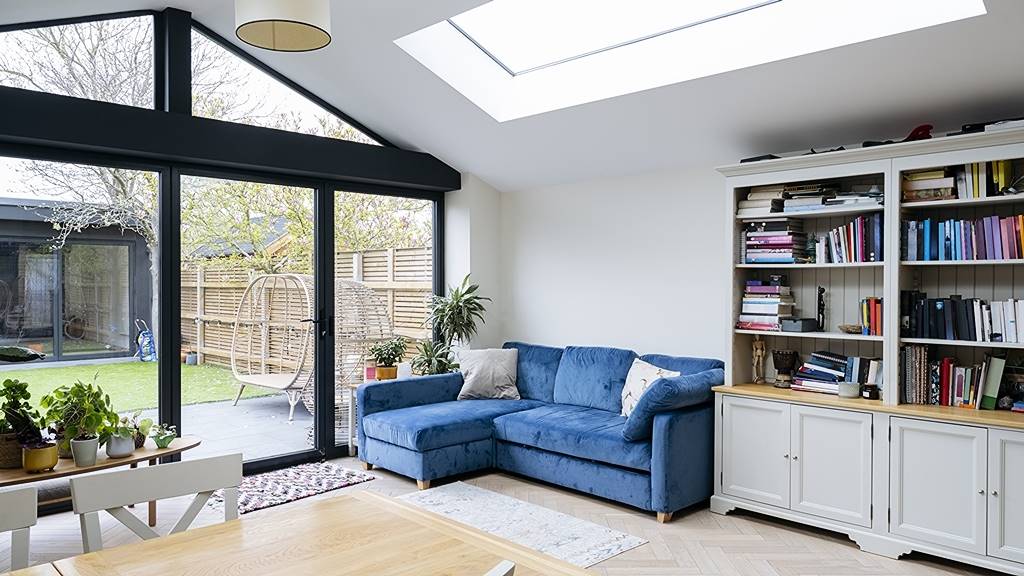 Bright home extension with blue sofa and garden-facing sliding doors