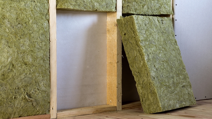 Rockwool insulation batts being installed in a wooden frame during drywall installation.