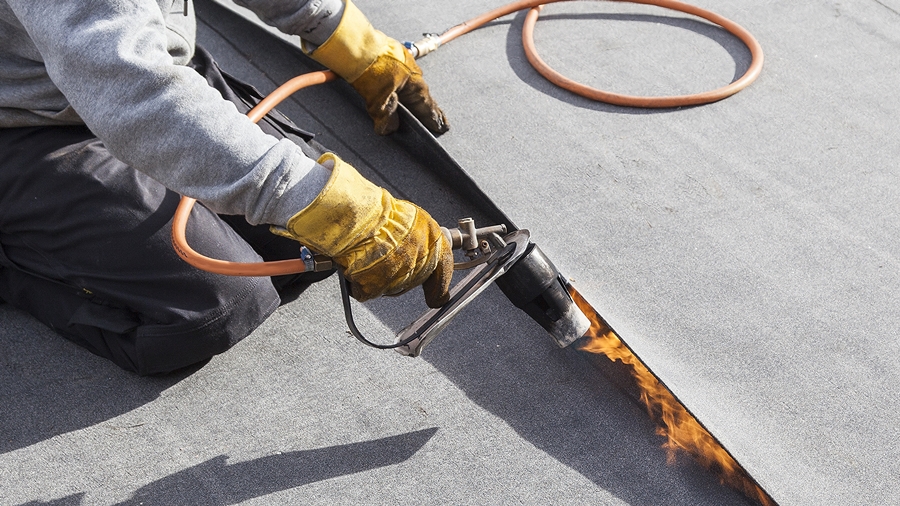 Professional installation of a torch-on felt flat roof using modified bitumen.