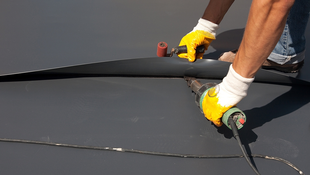 Installing PVC single-ply roofing membrane with heat-welding tools.