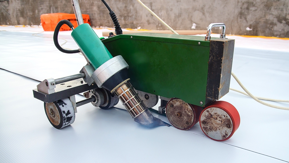 Automatic plastic welder sealing a PVC membrane for durable and waterproof flat roofing