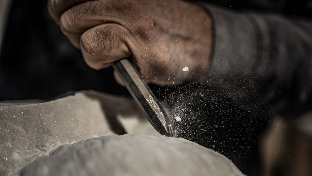 Stone mason chiselling stonework during repair and restoration
