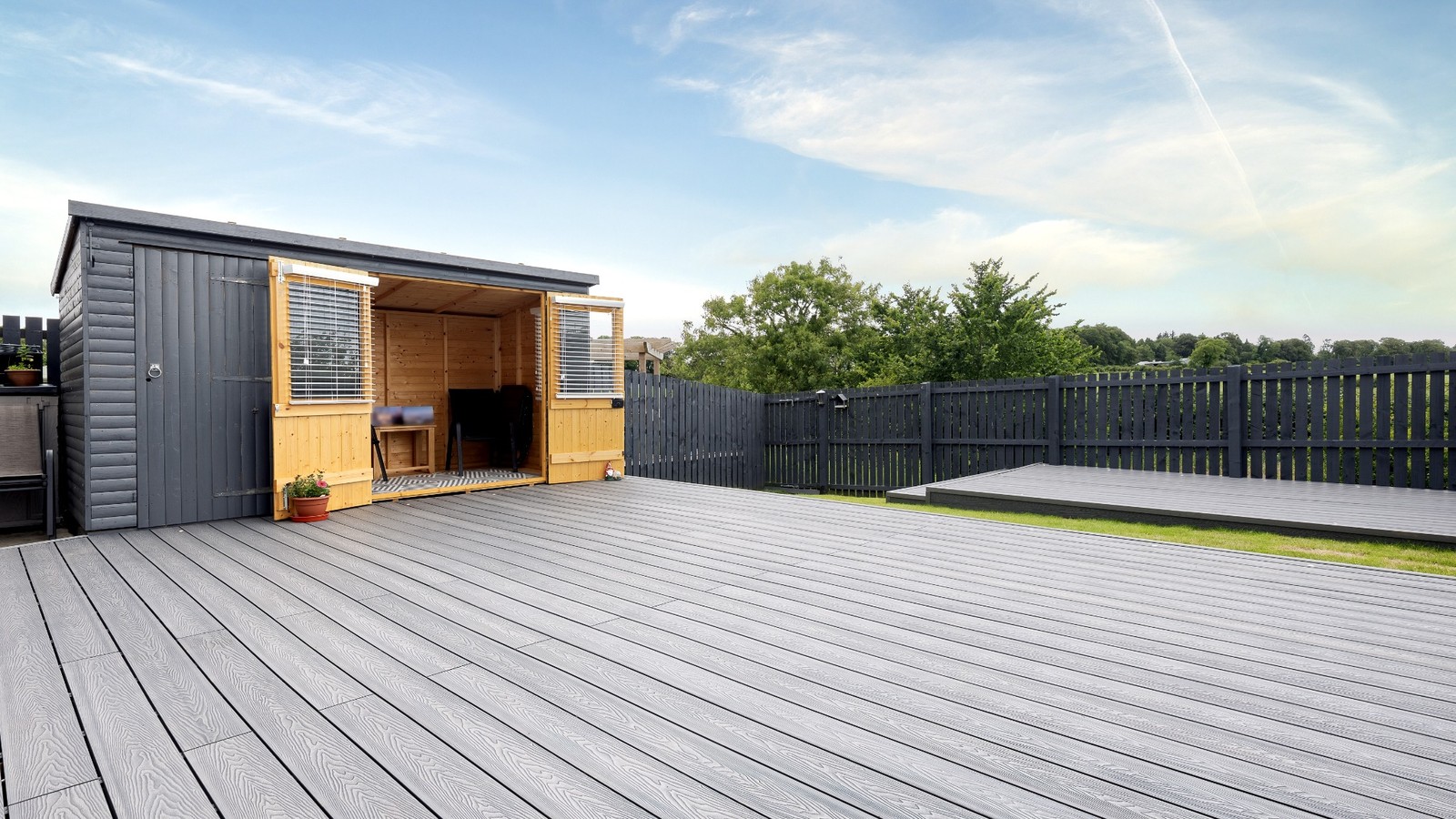 Large grey composite deck with timber garden building and surrounding fencing