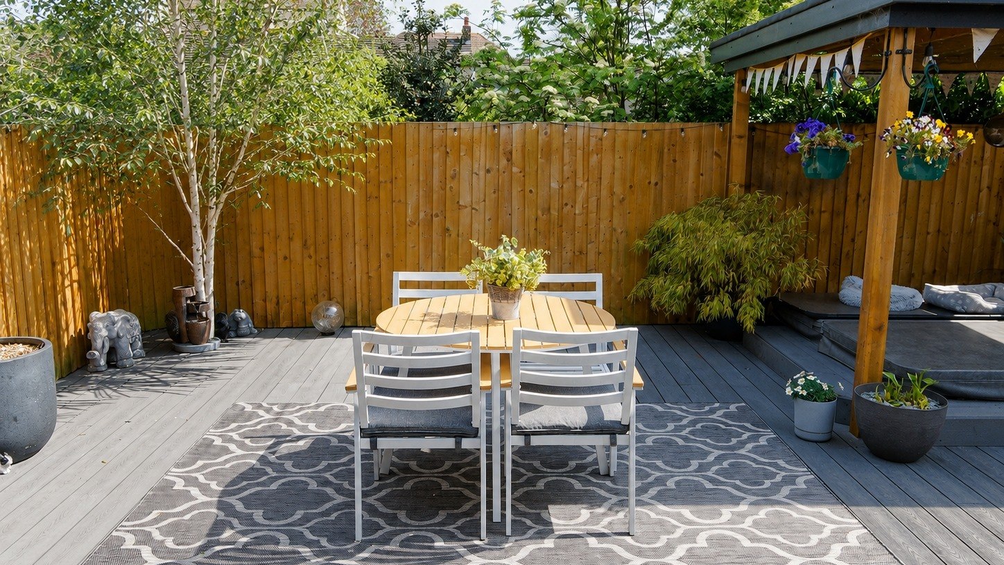 Decked garden seating area with dining table, timber fencing and covered seating area